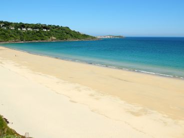 Yellow sand and blue sea on Carne beach in Cornwall.