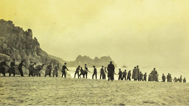 A sepia image of men pulling telegraph cables from the sea at Porthcurno.