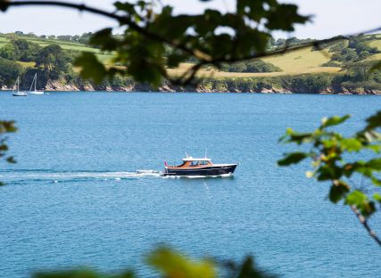 A boat on the River Fal seen through branches.