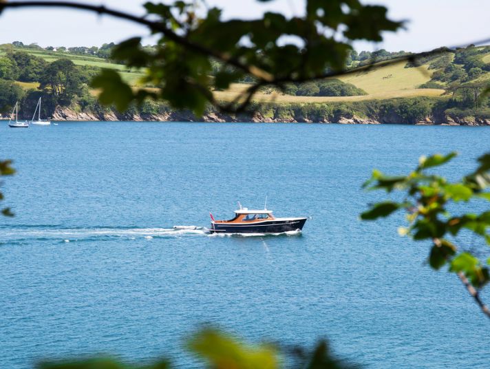 A boat on the River Fal seen through branches.