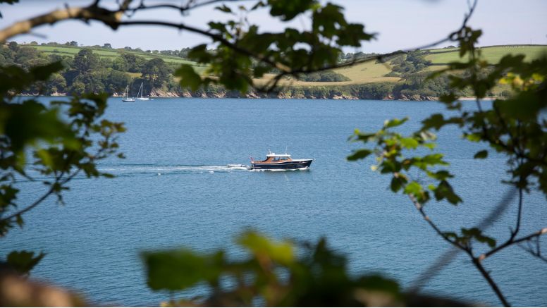 A boat on the River Fal spied through branches.
