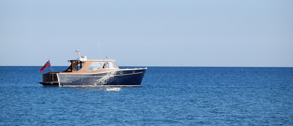 A boat drifts on a sparkling sea.