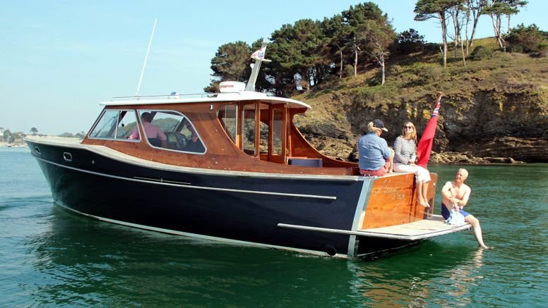 People enjoy the sun sitting on a motor boat anchored on the River Fal.