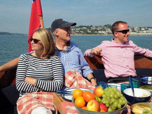 Friends enjoy a picnic in the sun on the back of a boat in south Cornwall.