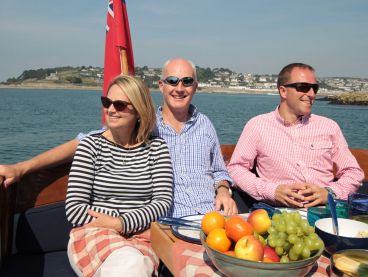 Friends enjoy sun and fruit while sailing the River Fal.