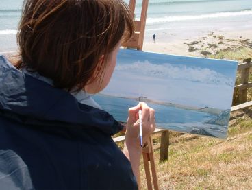 A woman paints the Cornish coast during an art holiday.