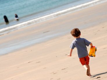 A little boy runs along Carne Beach towards the sea.