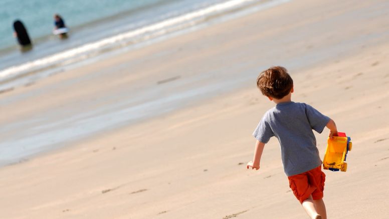 A little boy runs along Carne Beach towards the sea.