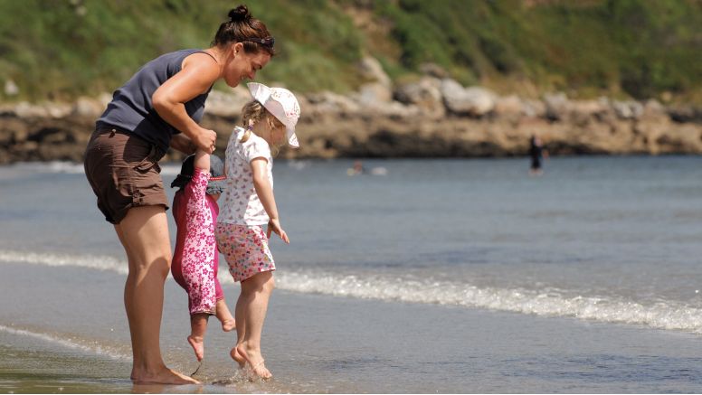 A mother and two children play on Carne Beach on the south coast of Cornwall.