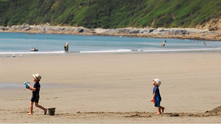 Two children play on the sand of Carne Beach, a secret beach near Truro in Cornwall.