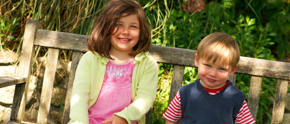 Two children sit on a bench in The Nare hotel grounds.