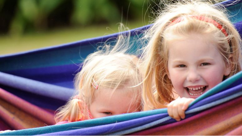 Two girls play hide and seek in a hammock at The Nare hotel.