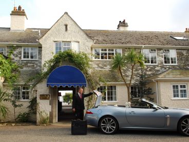 Outside The Nare hotel, the concierge unloads a guest's luggage from the hotel courtesy car.