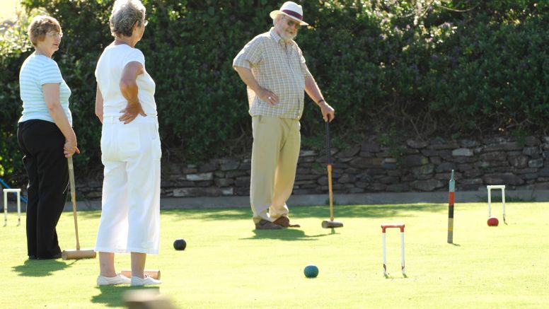 A party plays a game of croquet in the sun.