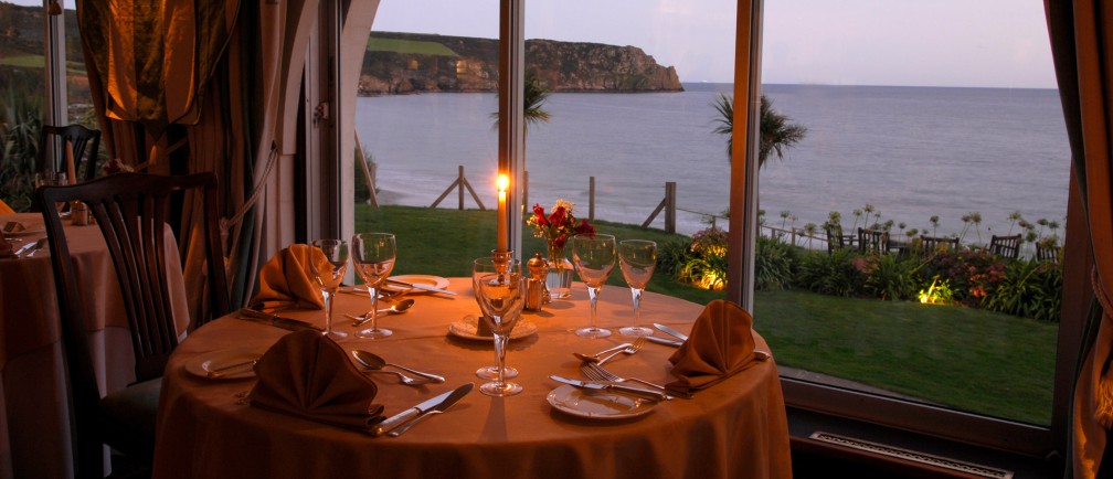 A candlelit table in the dining room at The Nare hotel in Cornwall, with panoramic sea views.