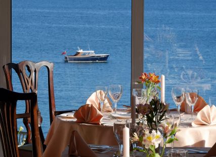 The Nare hotel dining room, with tables set and panoramic sea views.