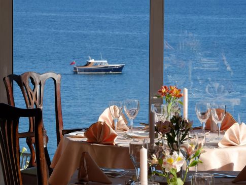The Nare hotel dining room, with tables set and panoramic sea views.