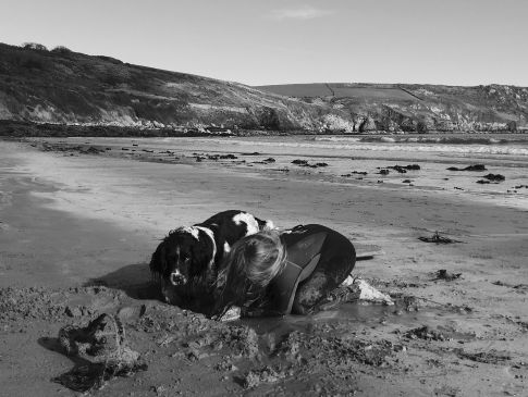 A child and their dog dig a hole on Carne Beach in Cornwall.