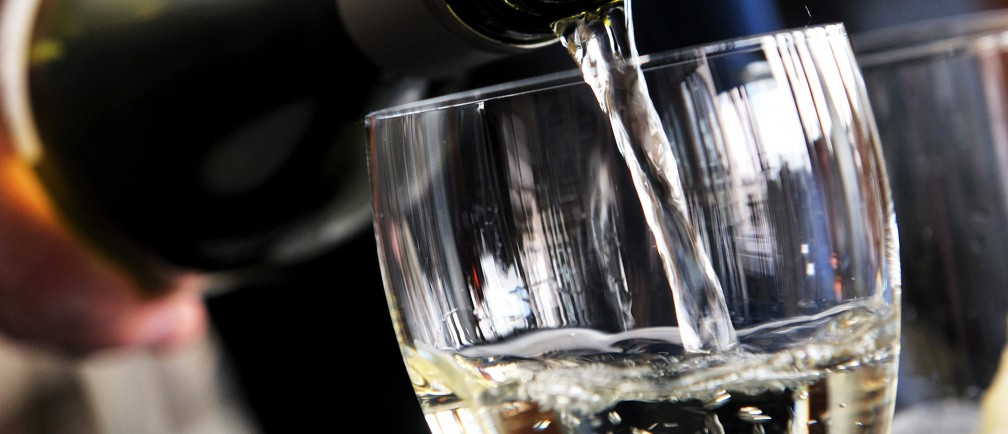 A glass of white wine being poured.