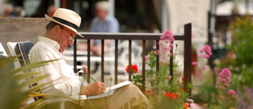 A man jots in a notebook as he sits in The Nare hotel gardens.