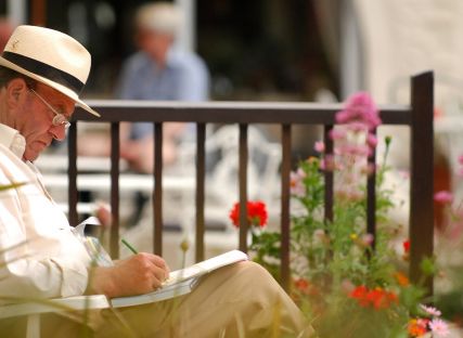 A man jots in a notebook as he sits in The Nare hotel gardens.