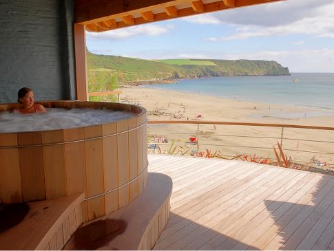 A woman enjoys the outdoor hot tub looking out over Carne Beach.