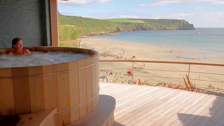 A woman enjoys the outdoor hot tub looking out over Carne Beach.