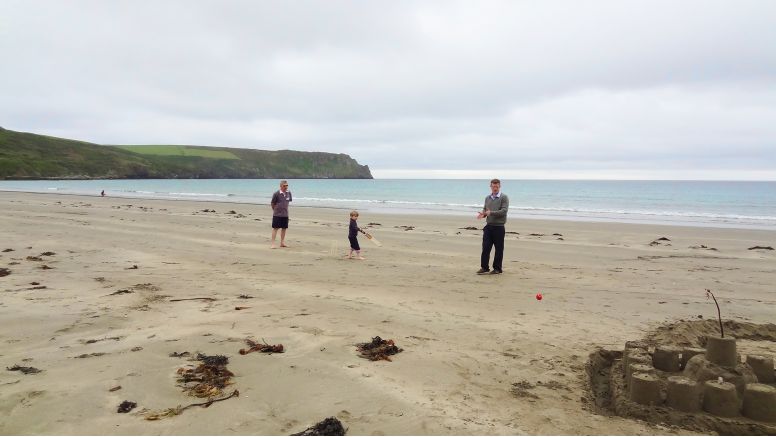 Grandfather, father and young son playing cricket on Carne Beach