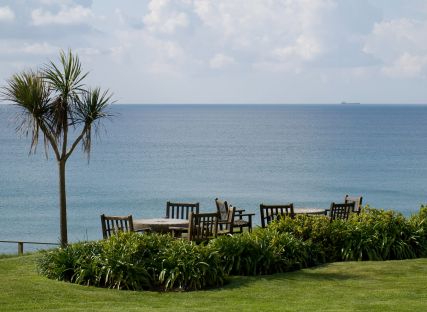 Garden furniture in The Nare hotel gardens and the sea beyond.