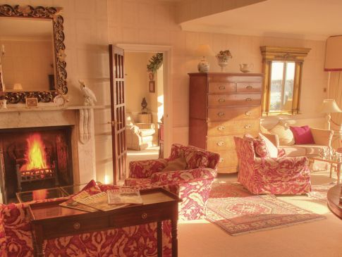The drawing room at The Nare, with a fire blazing in the fireplace.