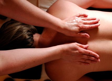 A masseuse massages a woman's back.