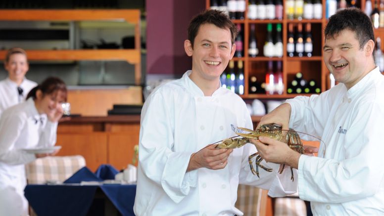 Some of the kitchen staff holding a lobster.
