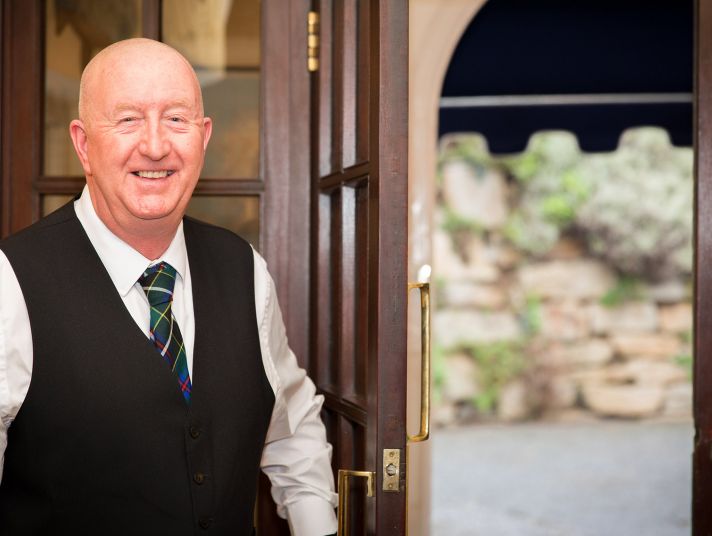 A smiling member of staff opens the door to The Nare hotel.