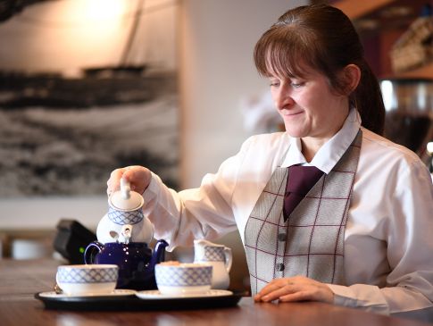A member of staff at The Quarterdeck restaurant pours water into a teapot.