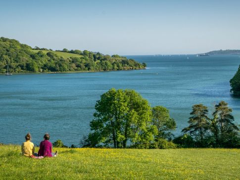 Two people sat overlooking where the Fal River meets the Carrick Roads estuary