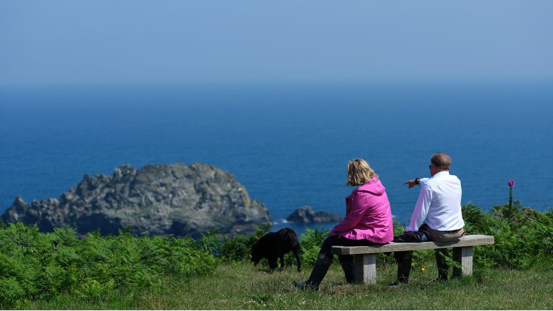 Two people sat on a bench overlooking the sea